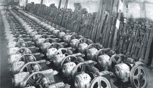 Foto d'epoca della produzione Bassetti Elevatori: lunghe file di argani allineati in un capannone